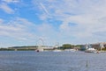 Panorama with boats, modern buildings and the Harbor Ferris under high skies with clouds.